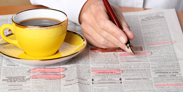 classified newspaper and with cup and pen